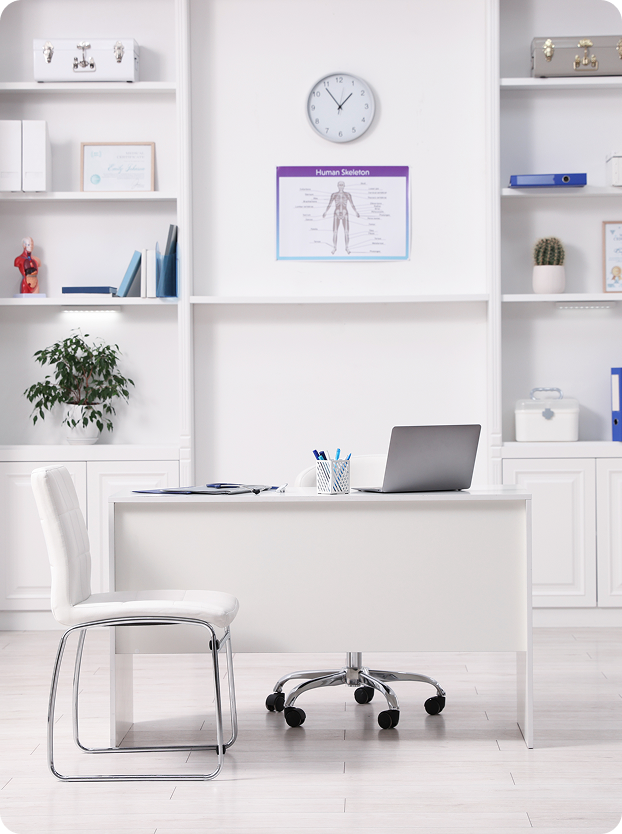 Bright treatment office with a desk, chair and shelves at Ryan Blossey Chiropractic