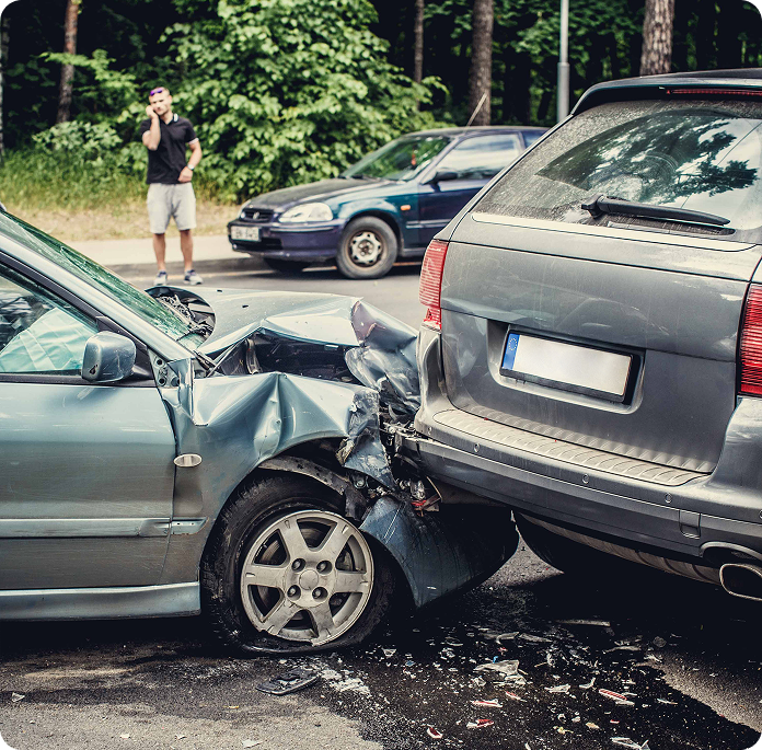 Two damaged cars after a collision with a driver on the phone in the background