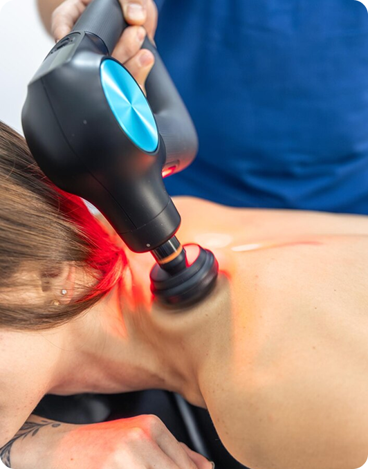 Percussive therapy device with red light applied to a patient's neck and shoulder