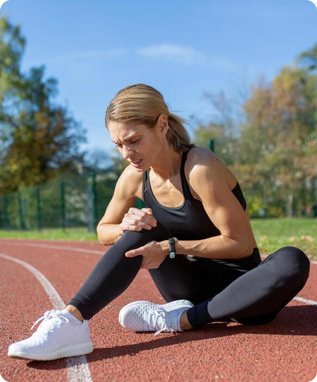 Runner sitting on a track holding her injured knee